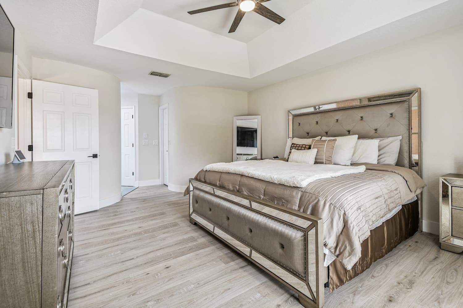 Master bedroom with tray ceiling and mirrored furniture